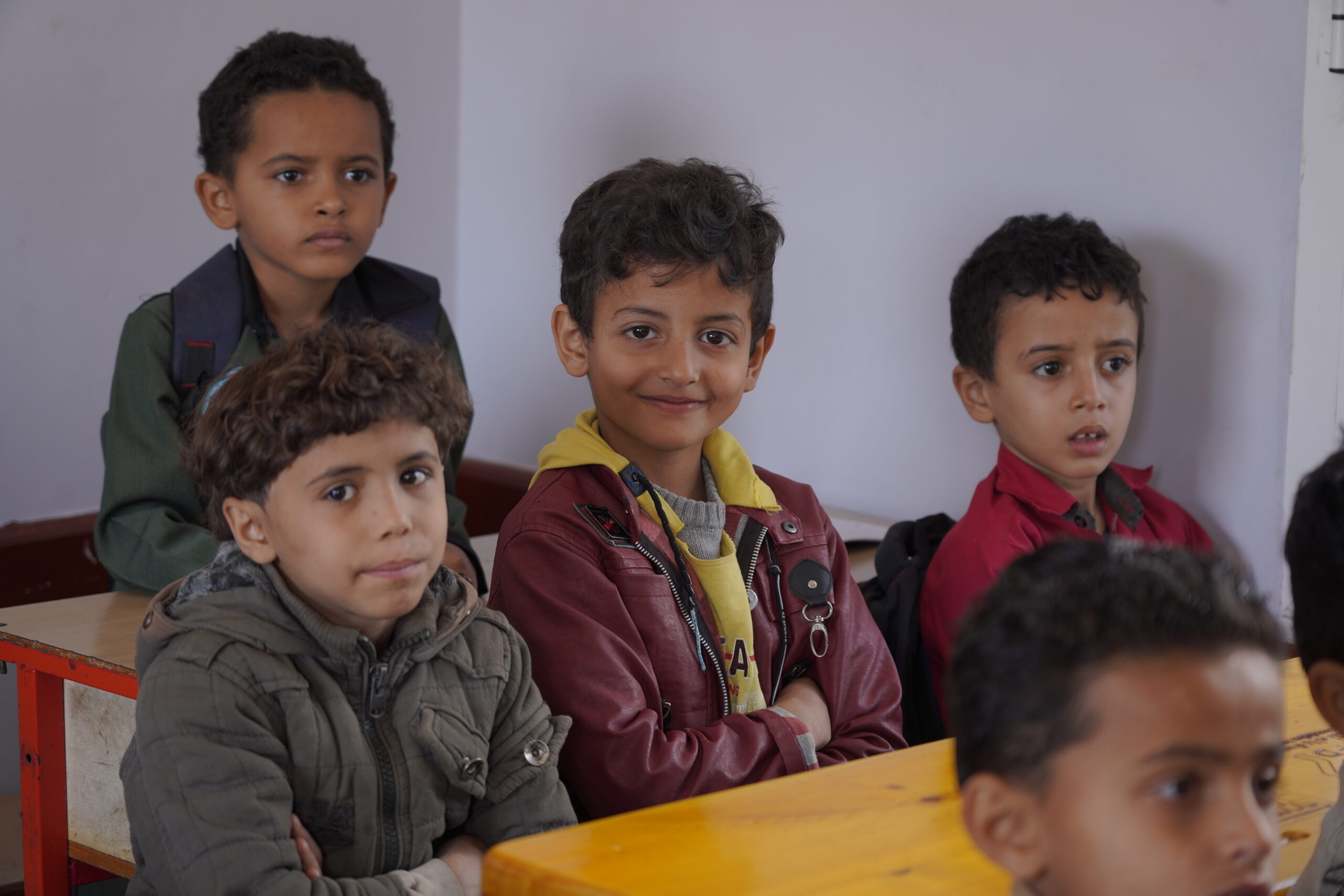 Boys at their desk smiling at school in Yemen