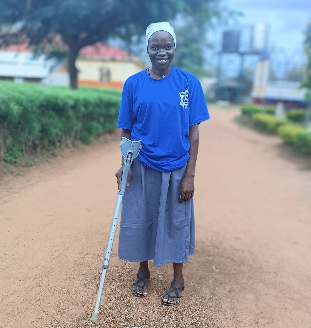 Young woman stands smiling at the camera holding an arm brace that helps her walk.