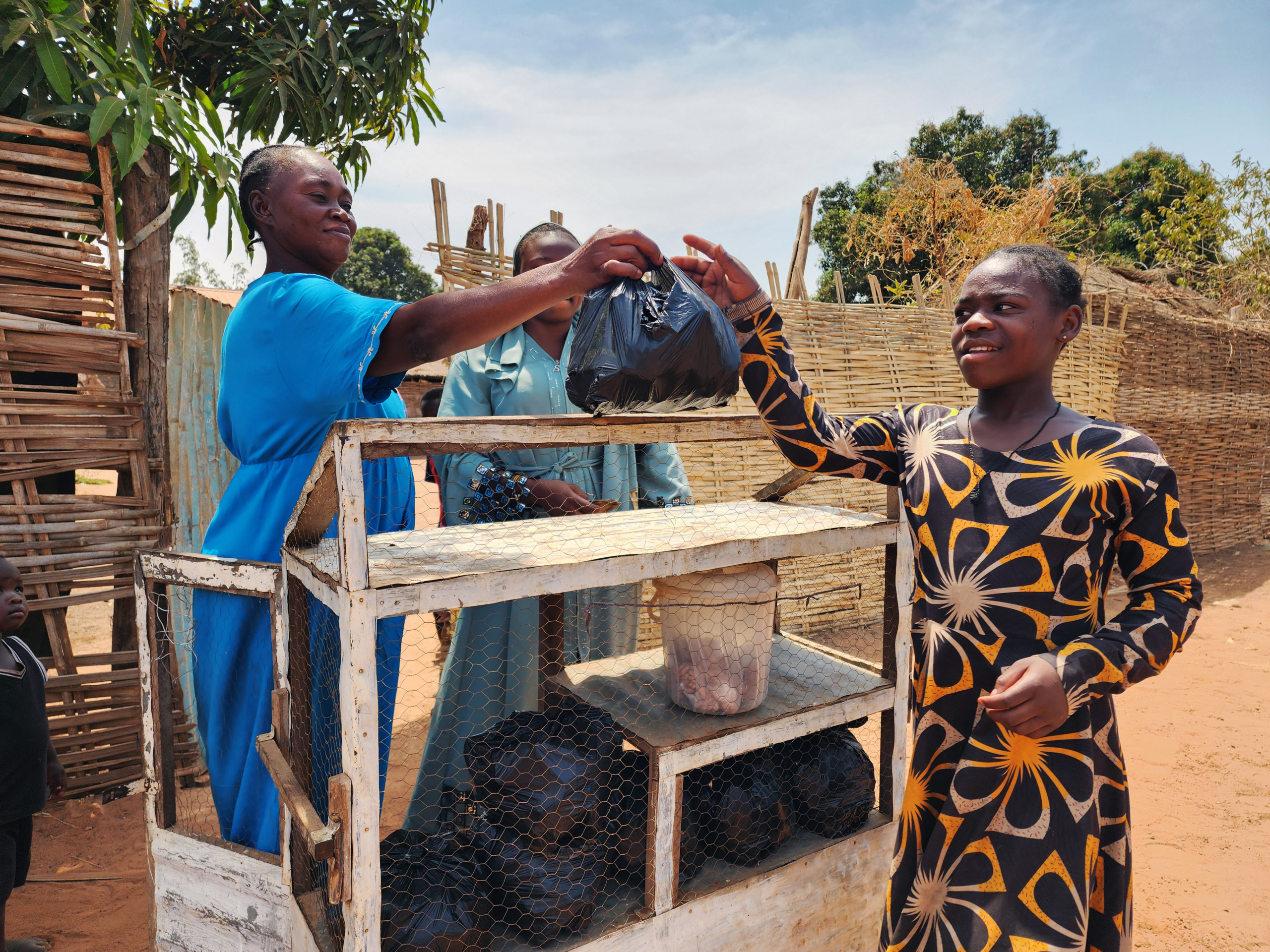 Small business in South Sudan, women handing a black bag to another woman