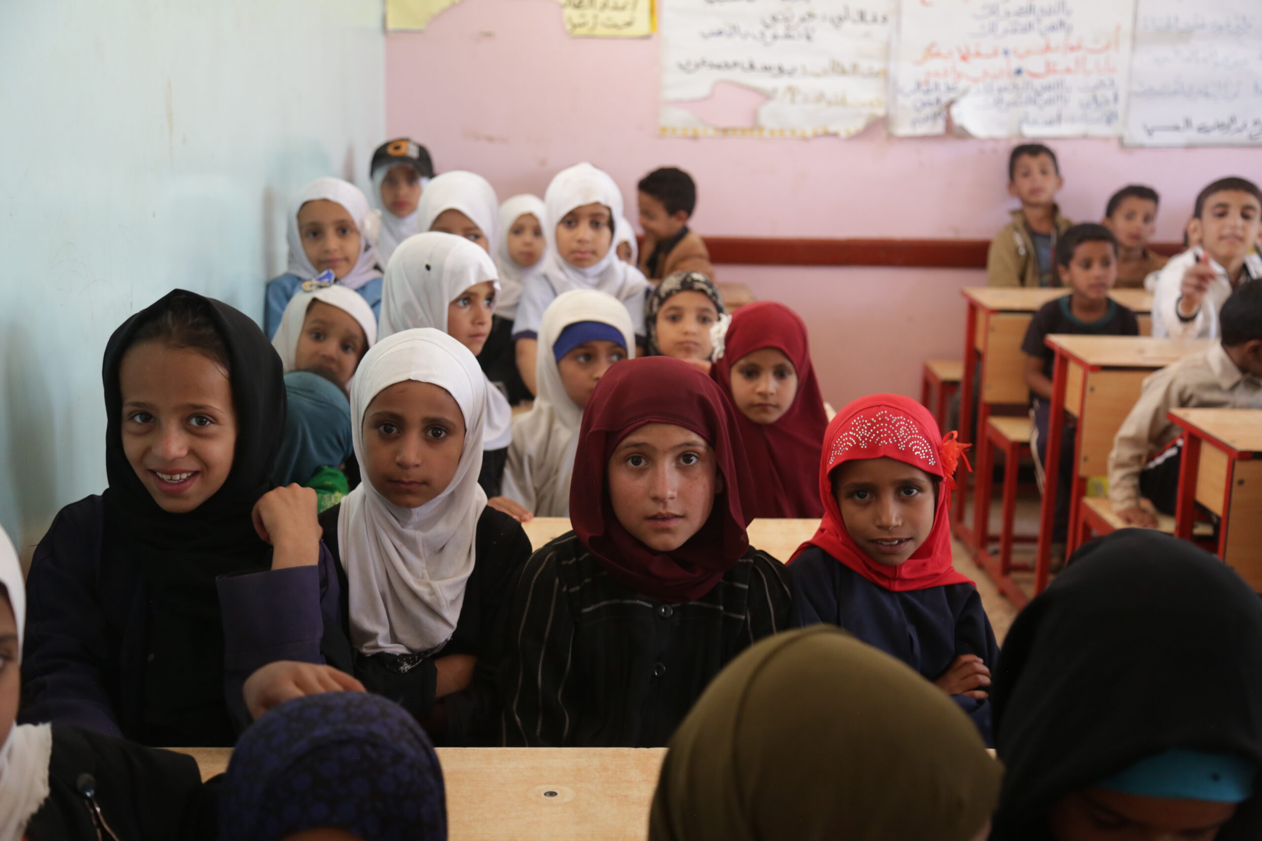 Children sitting at their desks, four to a desk, in Yemen.